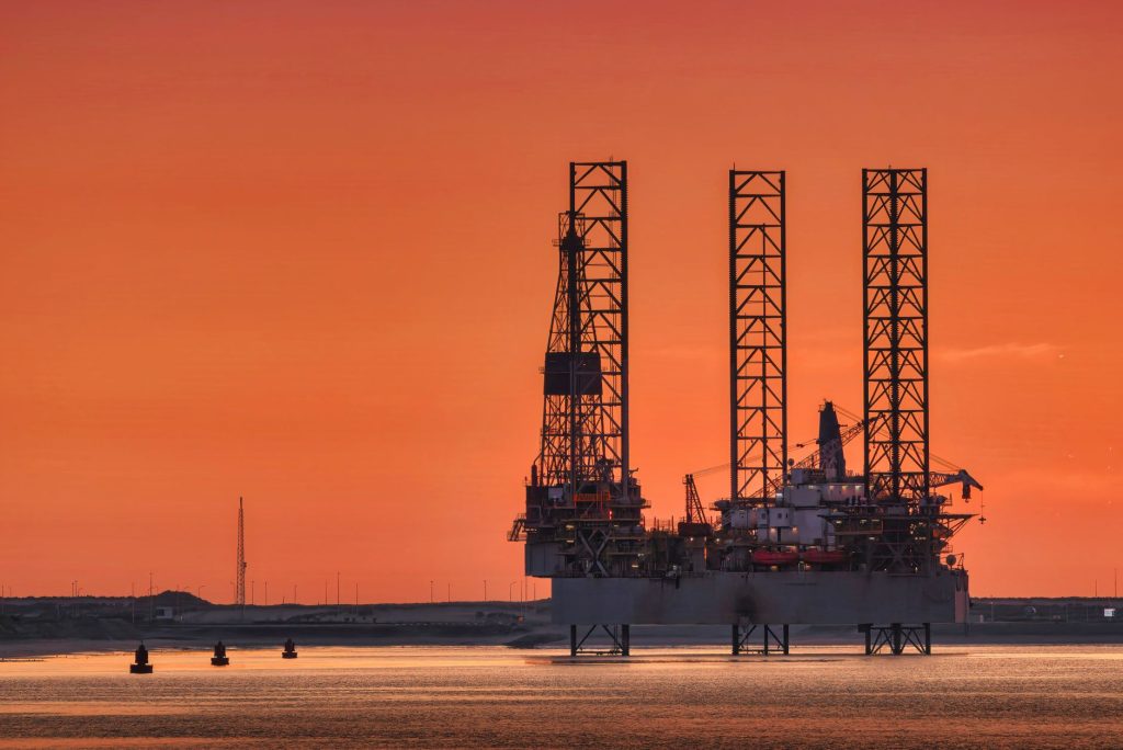 Oil drilling rigs silhouetted against a sunset